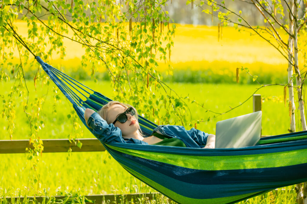 Woman in hammock working with laptop computer in hammock