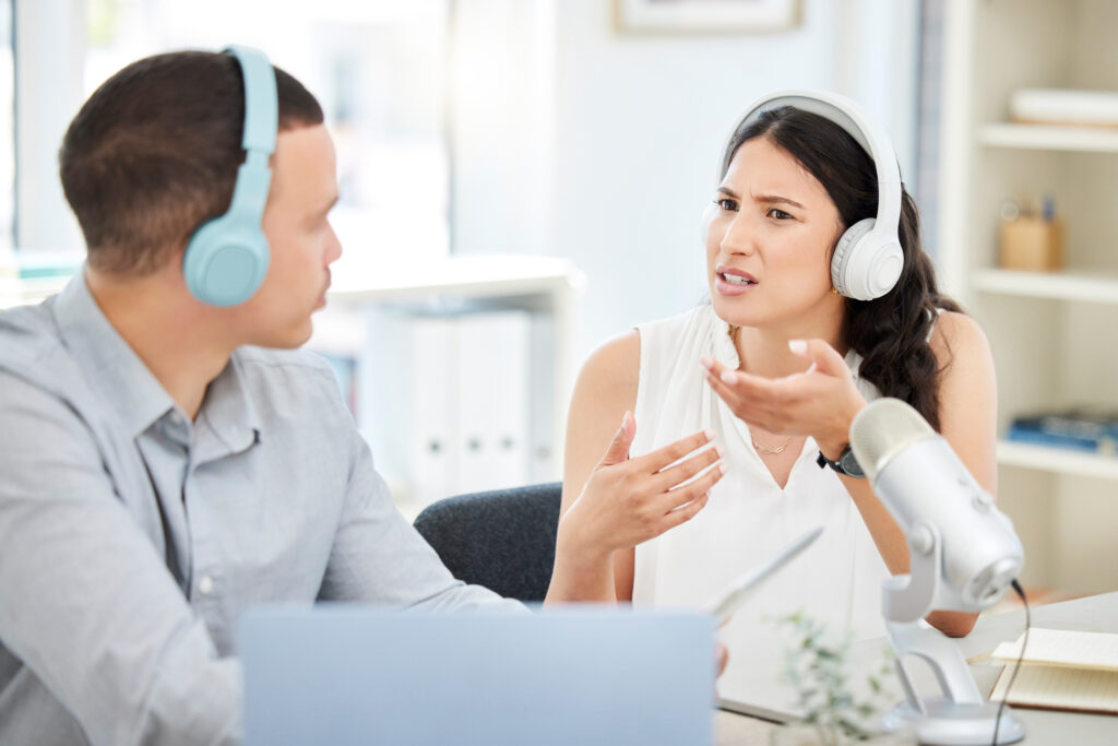 Shot of a young man and woman doing a broadcast in an office.